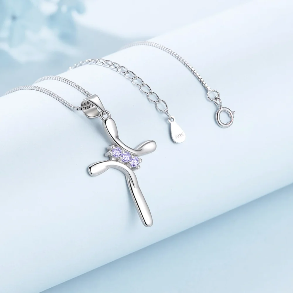 The June cross pendant, three purple stones, on pale blue cloth
