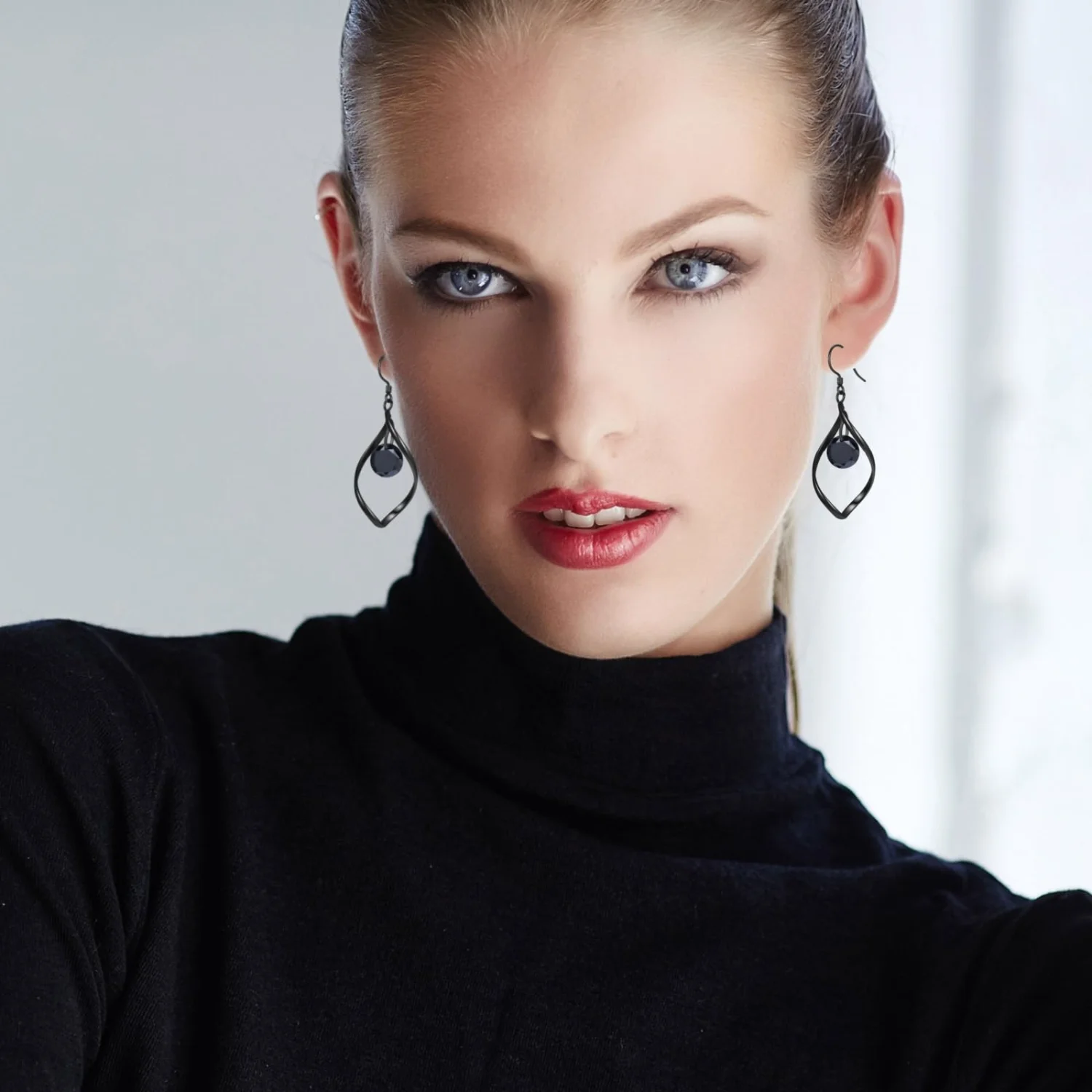 Black drop earrings hanging from a hand